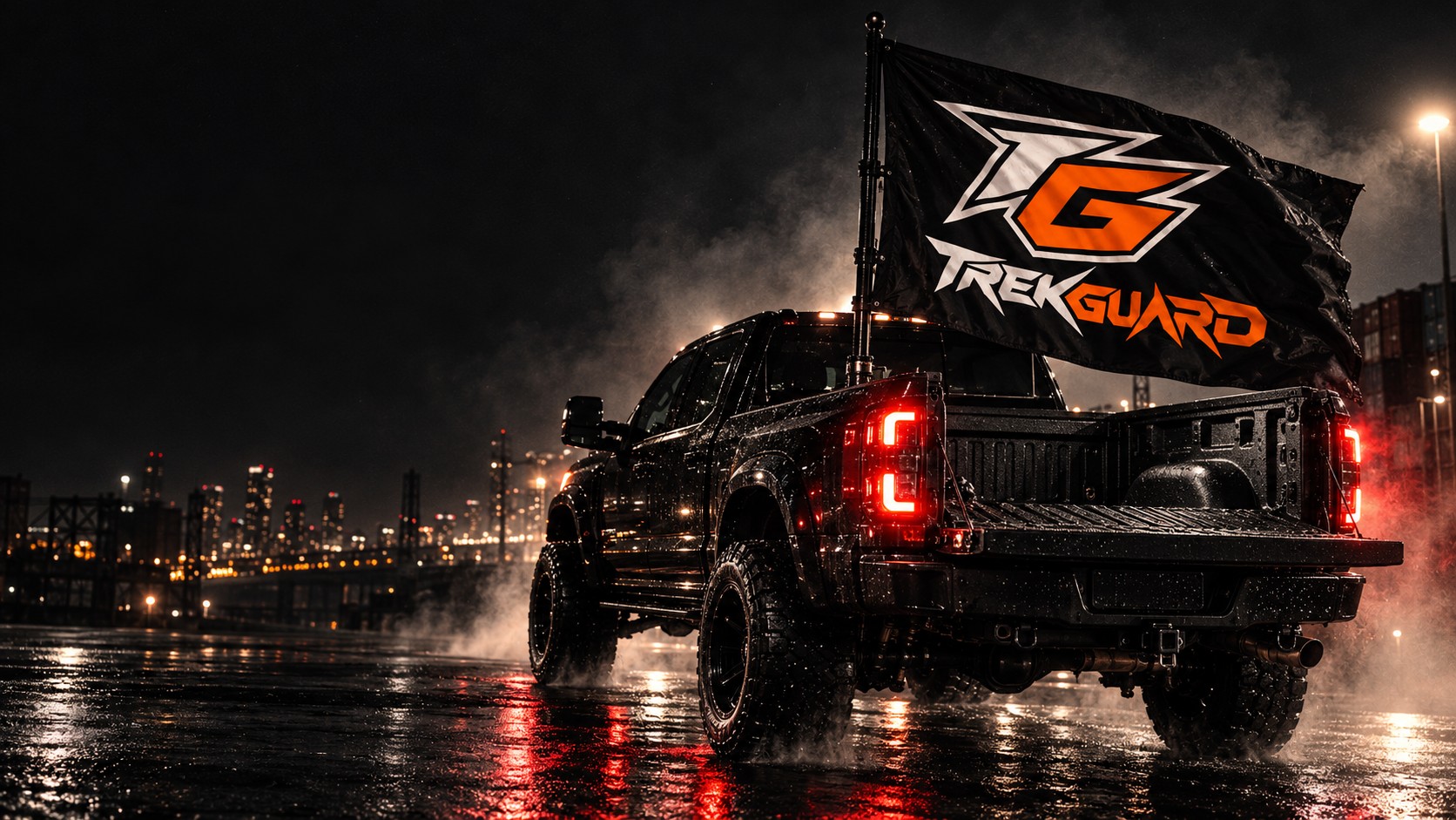 Black pickup flying a large TrekGuard TG flag on a nighttime industrial street